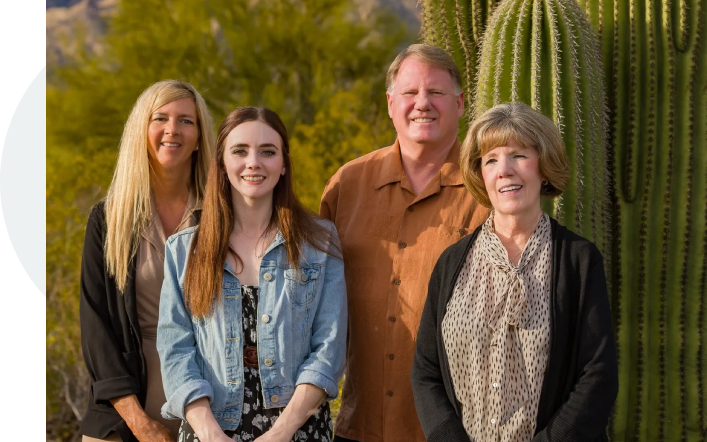 A family posing for a picture in front of a cactus.